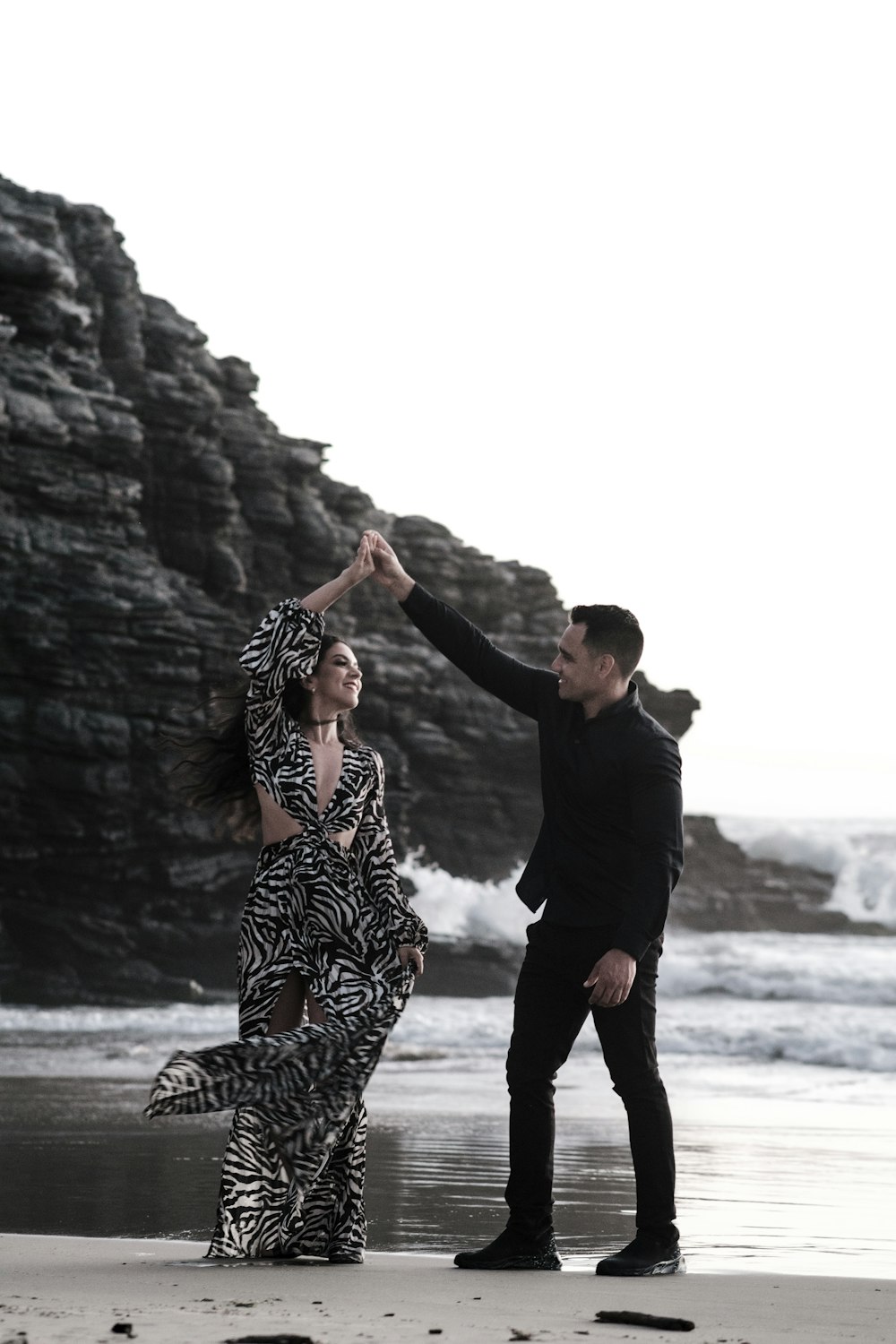 a man and woman dancing on a beach