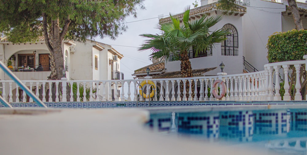 a pool with a white fence and a building with trees