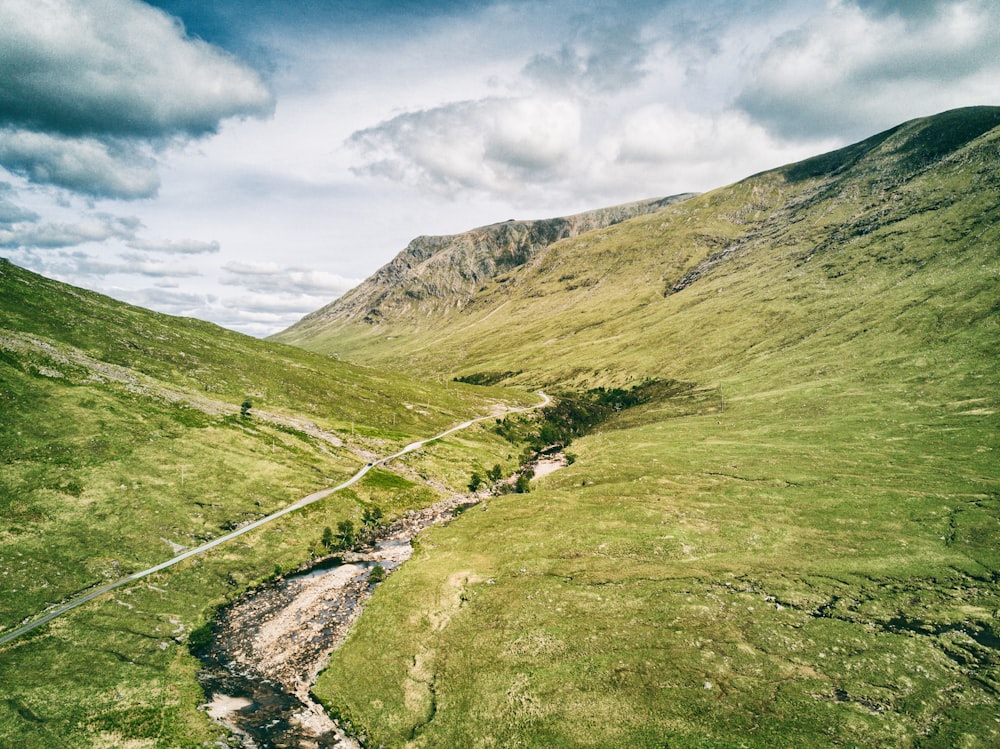 a stream running through a grassy valley