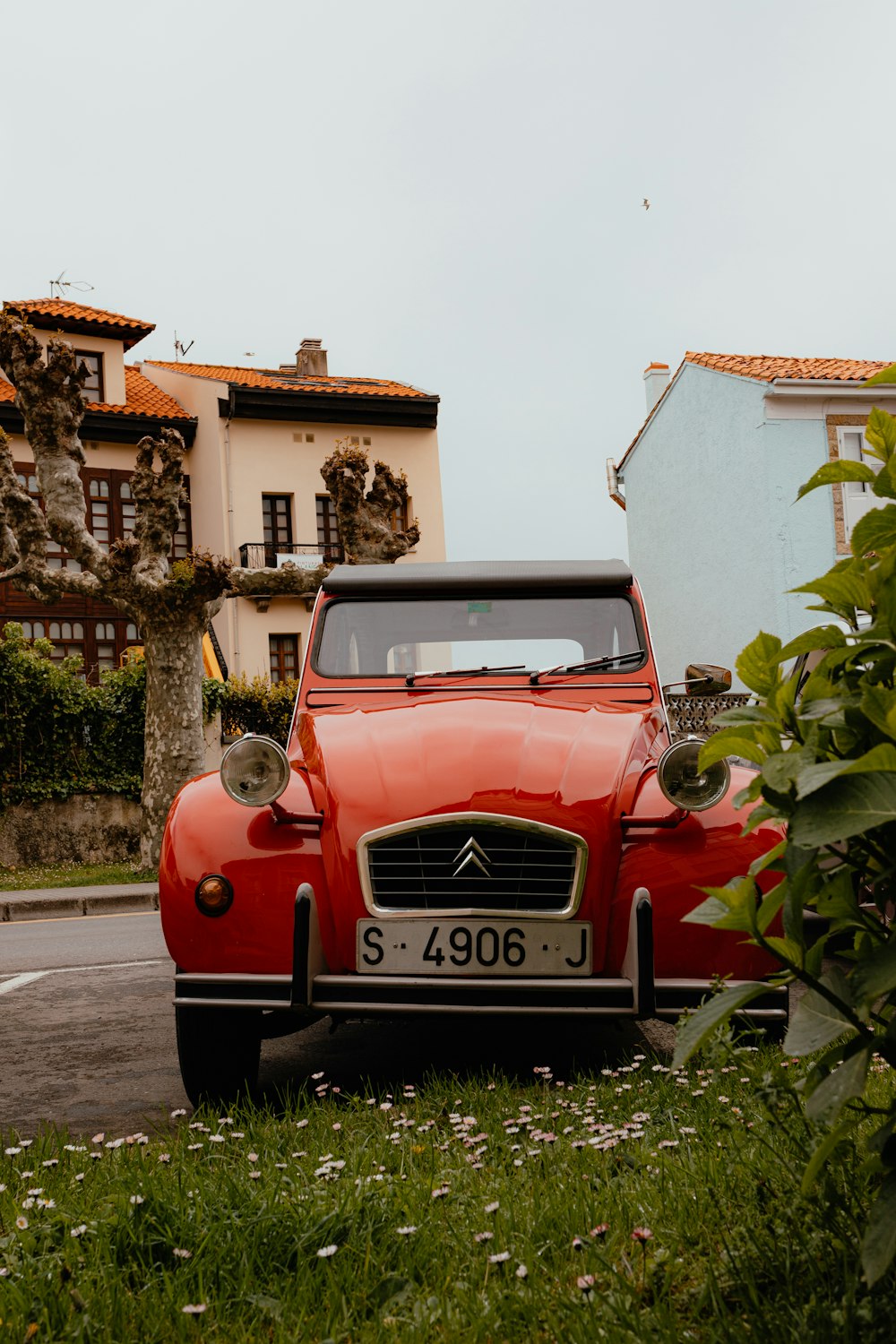 an old red car parked on the side of a road