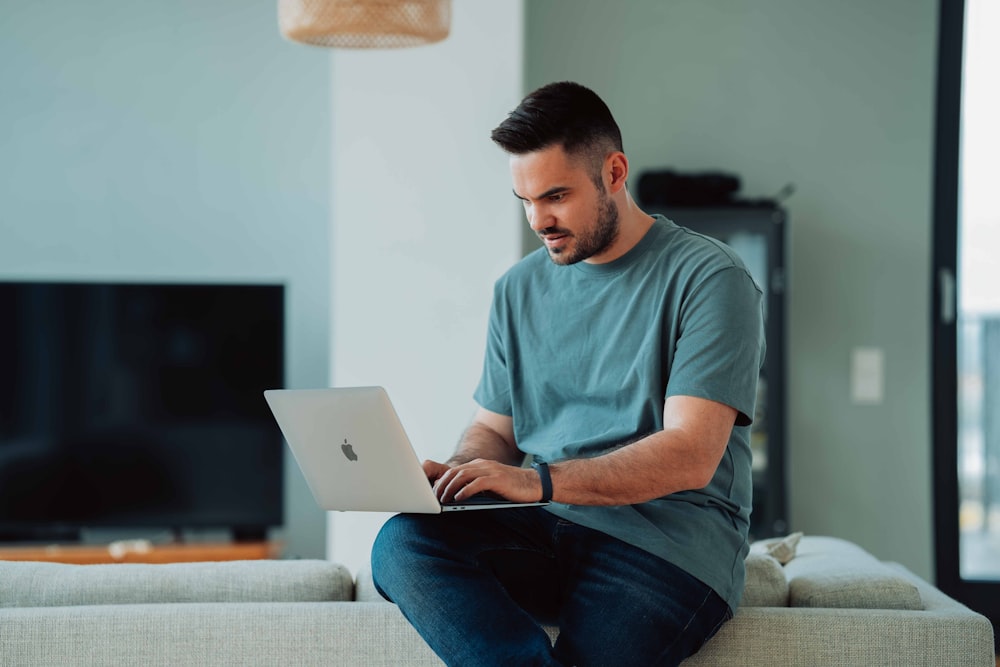 a man sitting on a couch using a laptop