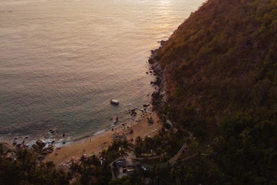 A cozy private boat anchored near a secluded beach in Ilhabela at sunset.