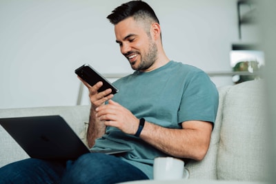 A person comfortably using a smartphone while relaxing on a cozy couch.