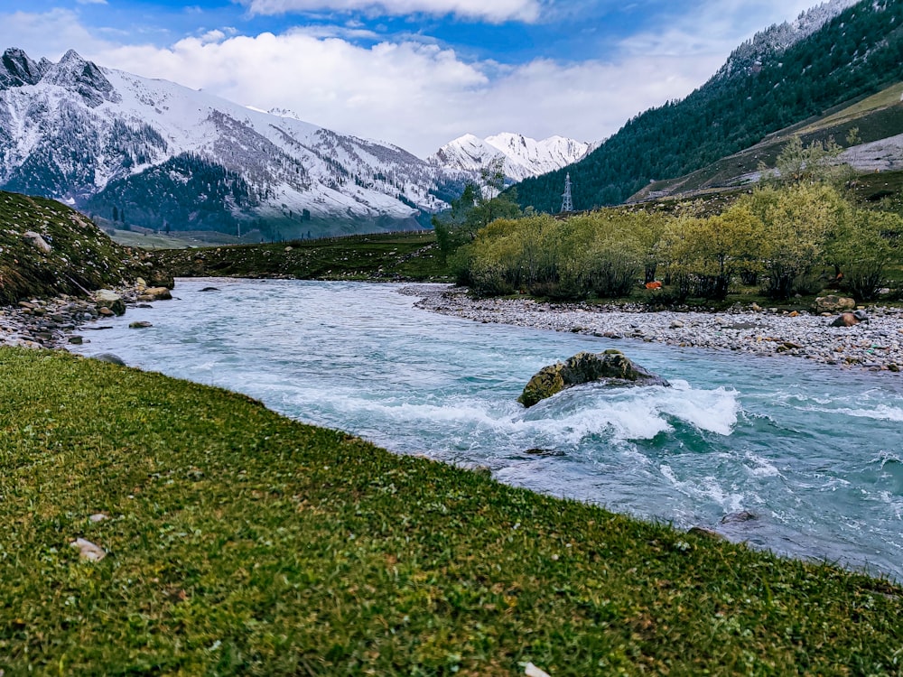 a river running through a valley with mountains in the background