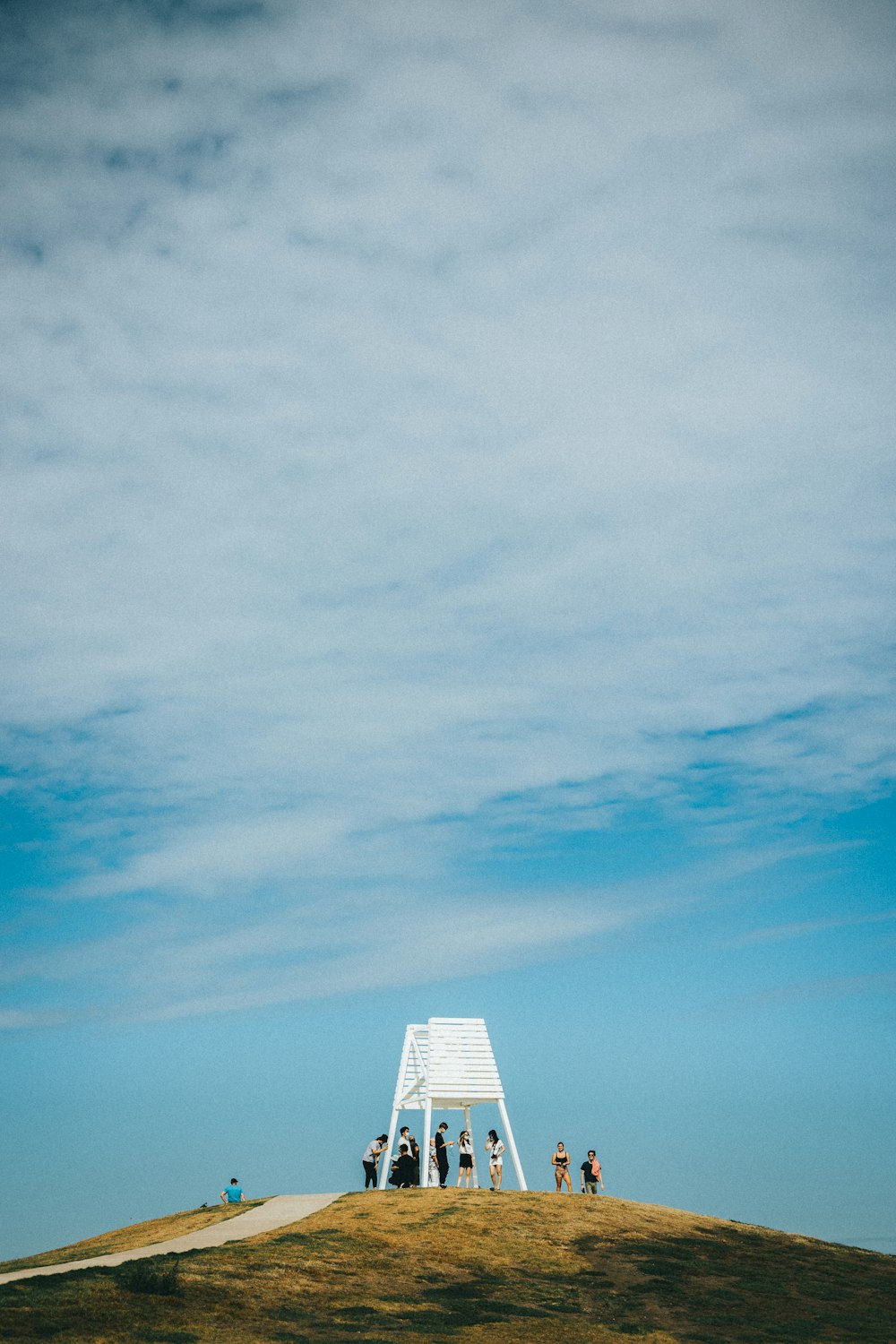 a group of people standing on a hill with a white structure in the background