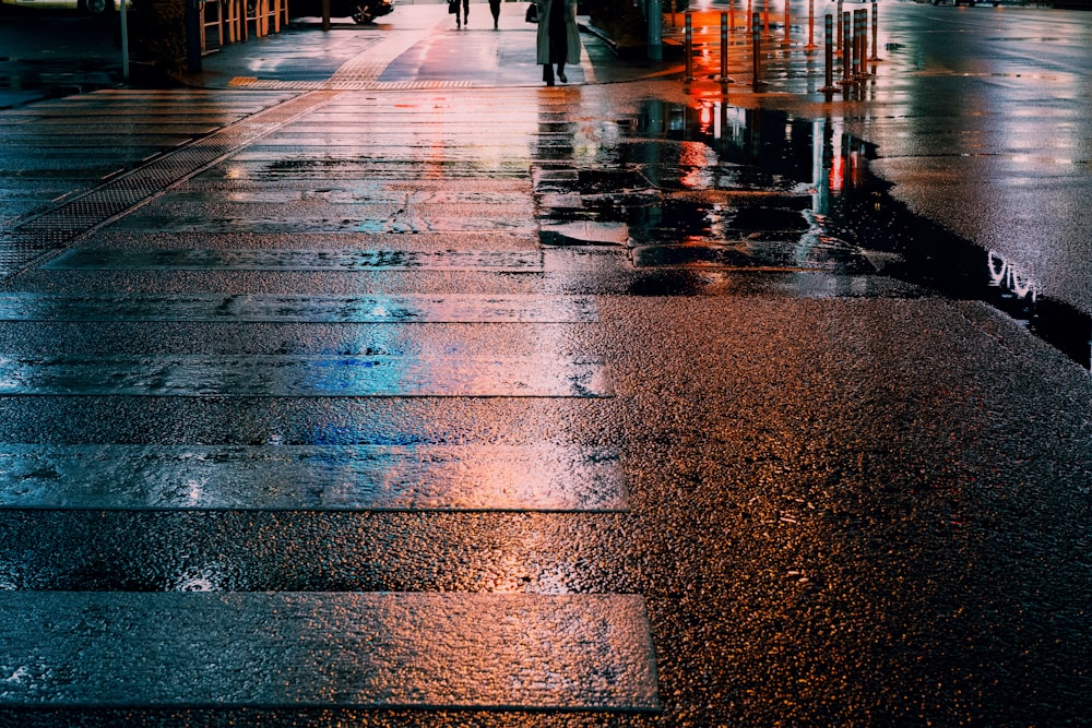 a wet sidewalk with people walking