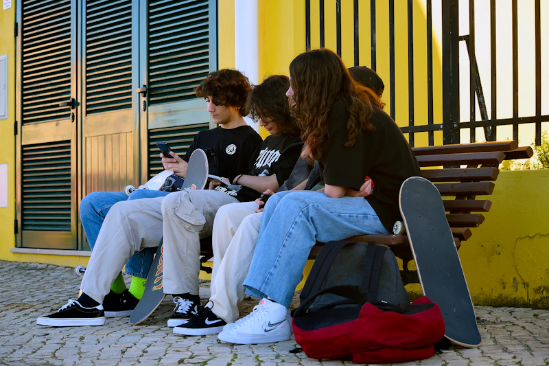 Young people sitting together on a bench working on laptops