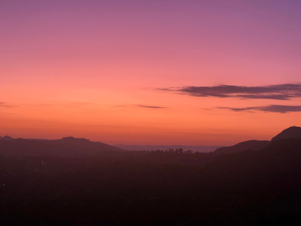 a landscape with hills and a pink sky