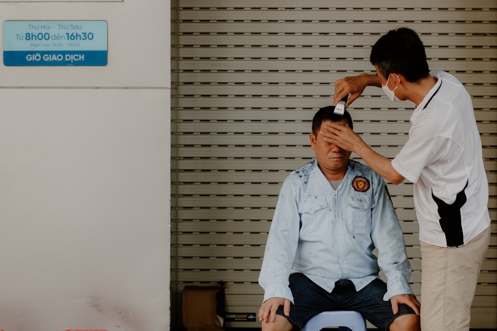 a man sitting on the floor with another man standing by him