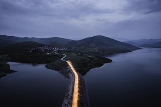 A serene landscape featuring a winding road leading through mountains under soft evening light.