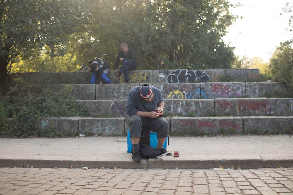 a man squatting on a sidewalk