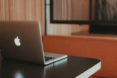 A professional workspace with a dark blue shield logo subtly displayed on a laptop screen, surrounded by legal documents and a secure lock symbol.