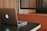A laptop with a distinctive logo is placed on a dark-colored table. The background features wooden paneling and a cushioned booth, creating a cozy and professional atmosphere.