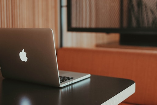 A laptop with a distinctive logo is placed on a dark-colored table. The background features wooden paneling and a cushioned booth, creating a cozy and professional atmosphere.