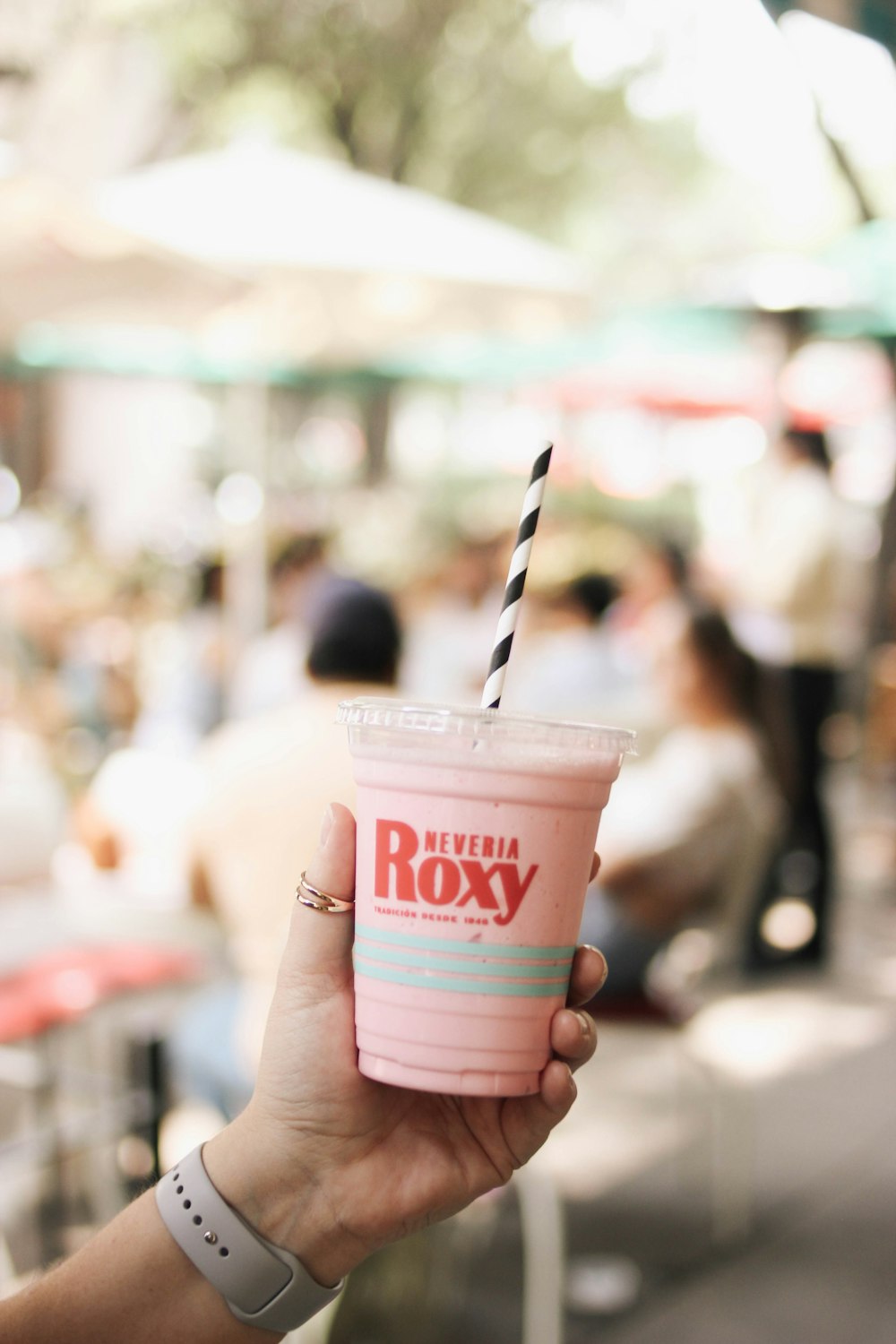 a hand holding a plastic cup with a straw and a straw