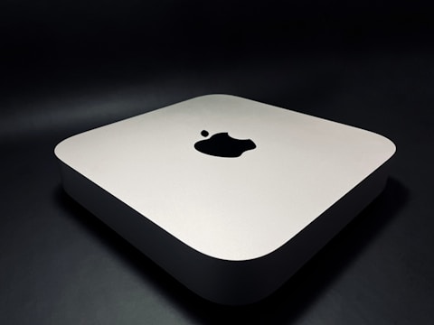 A sleek, minimalist electronic device with rounded edges, featuring a prominent logo on the top surface. The device rests on a dark surface, giving it a modern and sophisticated appearance.