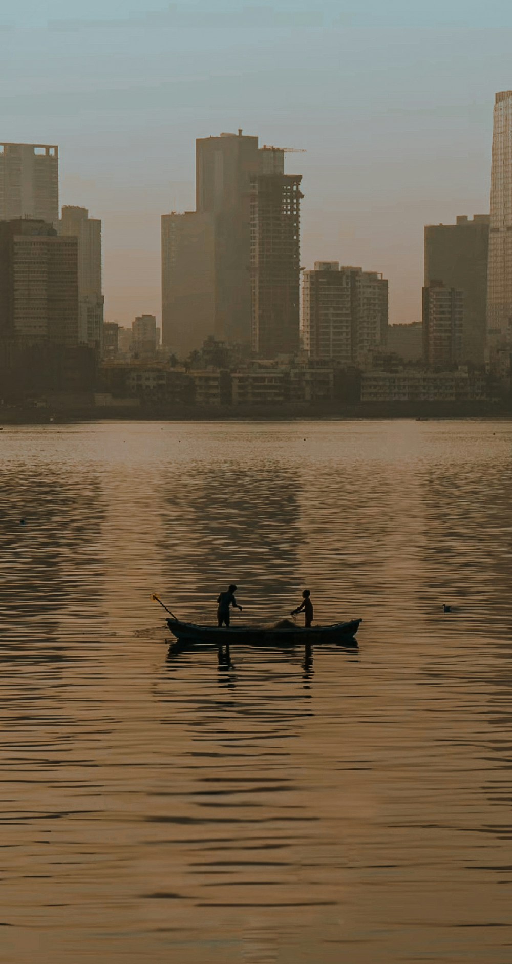 a couple of people in a boat on a body of water with a city in the background