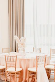 Luxurious wedding table setup with blush pink and gold accents under soft lighting.
