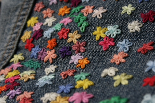A colorful embroidered patch featuring intricate floral patterns on denim fabric.