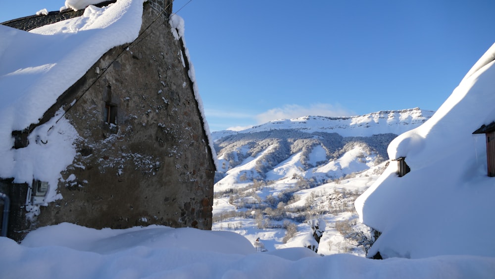 a stone building with snow on the ground and mountains in the background
