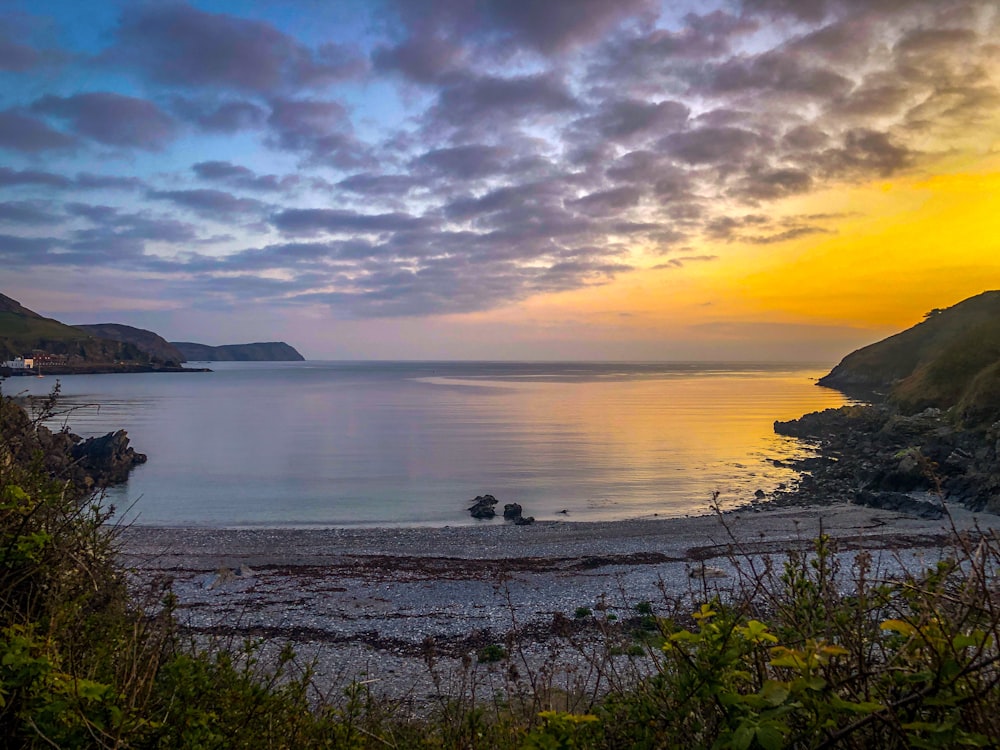 a beach with a body of water and hills in the background