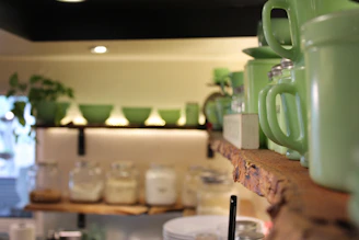 A stylish kitchen setup displaying green ceramic dishes and matching utensils on wooden shelves.