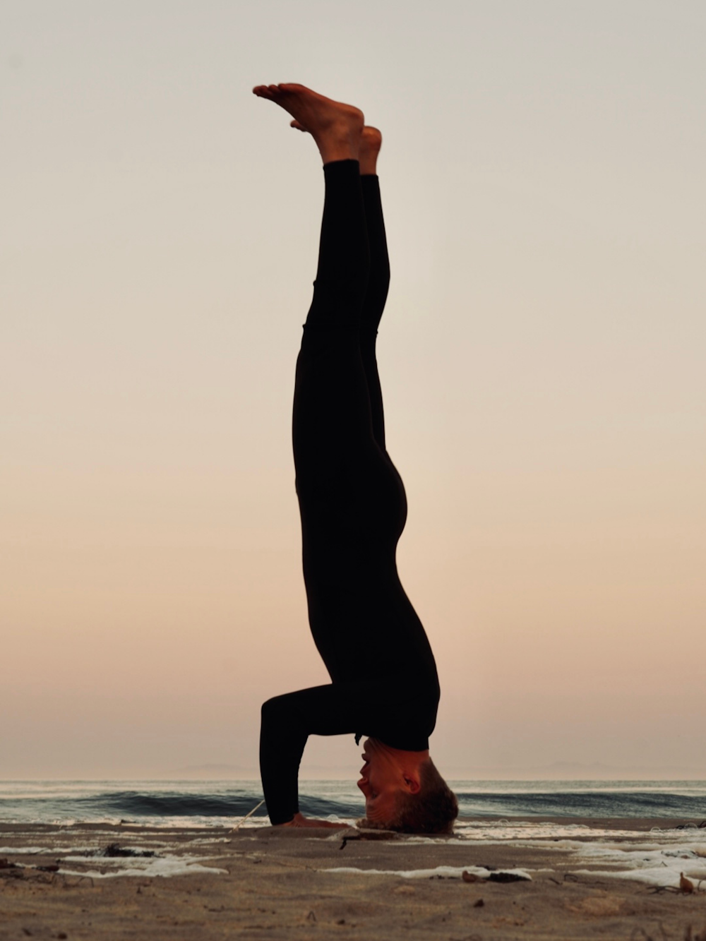 a man doing a handstand on a beach