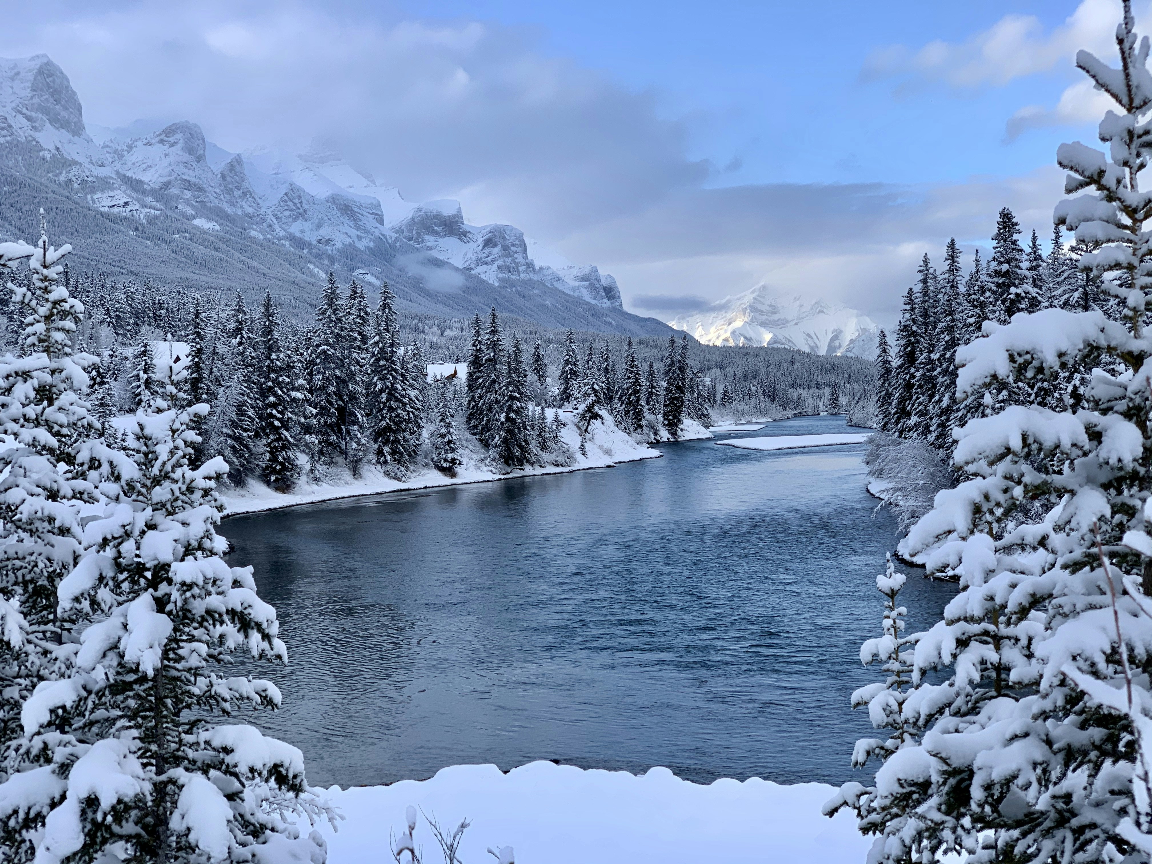a river surrounded by snow covered trees
