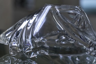 A minimalist sculpture blending glass and metal, reflecting ambient colors.