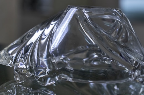 A minimalist sculpture blending glass and metal, reflecting ambient colors.