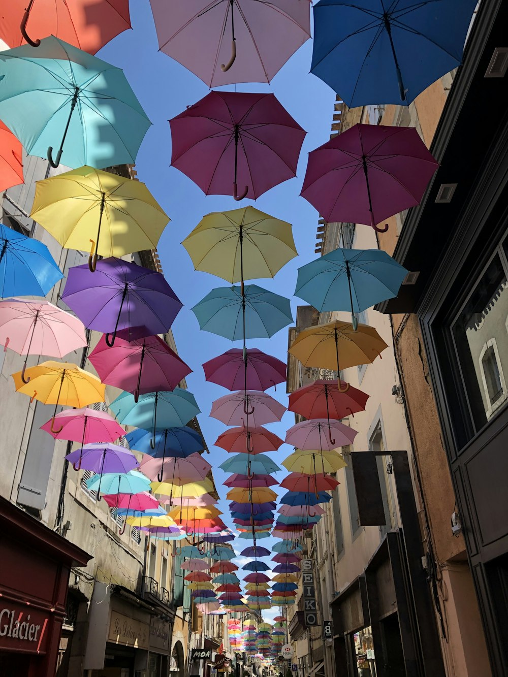 a group of colorful umbrellas swing from a building