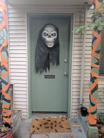 A spooky garage entrance lit with eerie green and purple lights, decorated with friendly ghost figures and cobwebs.