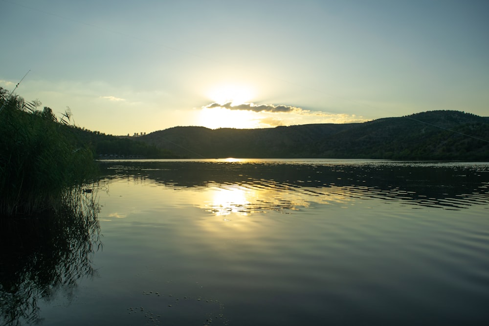 a body of water with trees and hills in the background