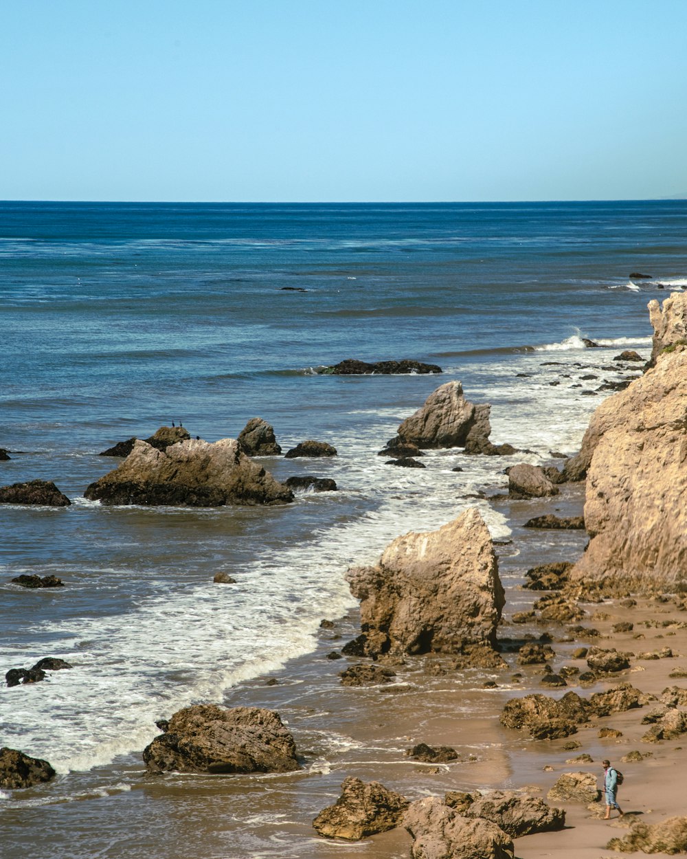 a rocky beach with a body of water in the background