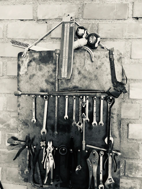 A neatly organized wall-mounted tool rack featuring hand tools with metallic and orange accents.