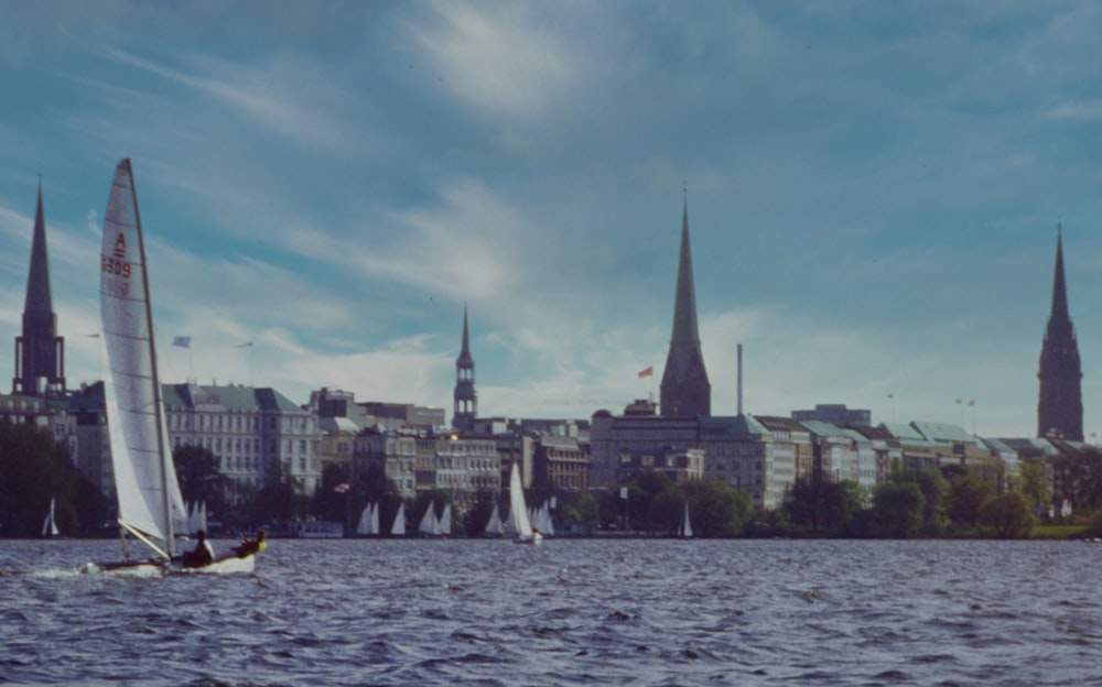 a group of sailboats on the water with a city in the background