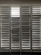 Vertical window blinds are evenly arranged, allowing faint light to pass through, creating a pattern of light and shadow.