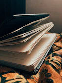 A close-up of a blank notebook open on a wooden desk under warm light.