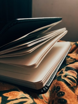 An open notebook with a pen resting on top, surrounded by a cozy atmosphere of warm light.