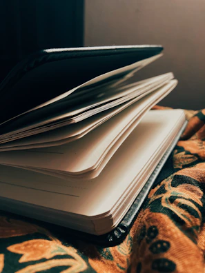 A close-up of a blank notebook open on a wooden desk under warm light.