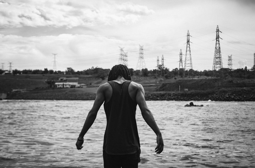 a person standing in front of a body of water with power lines in the background