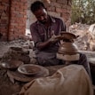 Artisan shaping clay on a pottery wheel in a sunlit studio