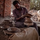 Artisan shaping clay on a pottery wheel in a sunlit studio