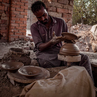 Artisan shaping a clay pot on a pottery wheel in a cozy studio filled with natural light.