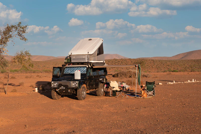 An expedition vehicle set up as a camp with its awning out in the desert
