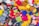 A pile of colorful knitted figures, each with distinct patterns and designs. Various characters are visible, including animals and humanoid figures, featuring bright and vibrant yarns in a mix of colors.