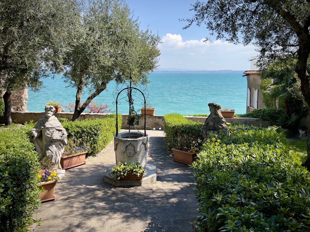 a statue of a person in a garden by the water