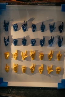 An array of small model hands displaying various hand signs and gestures. The hands are organized in four horizontal rows, with blue hands occupying the top two rows and yellow hands the bottom two rows.