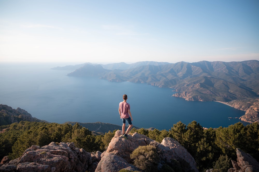 a man standing on a rock overlooking a body of water