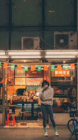 Close-up of a local guide smiling warmly, standing in front of a bustling street food stall.